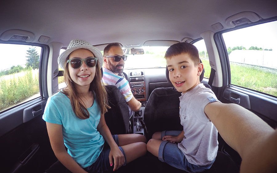 Kids and father taking selfie in still car